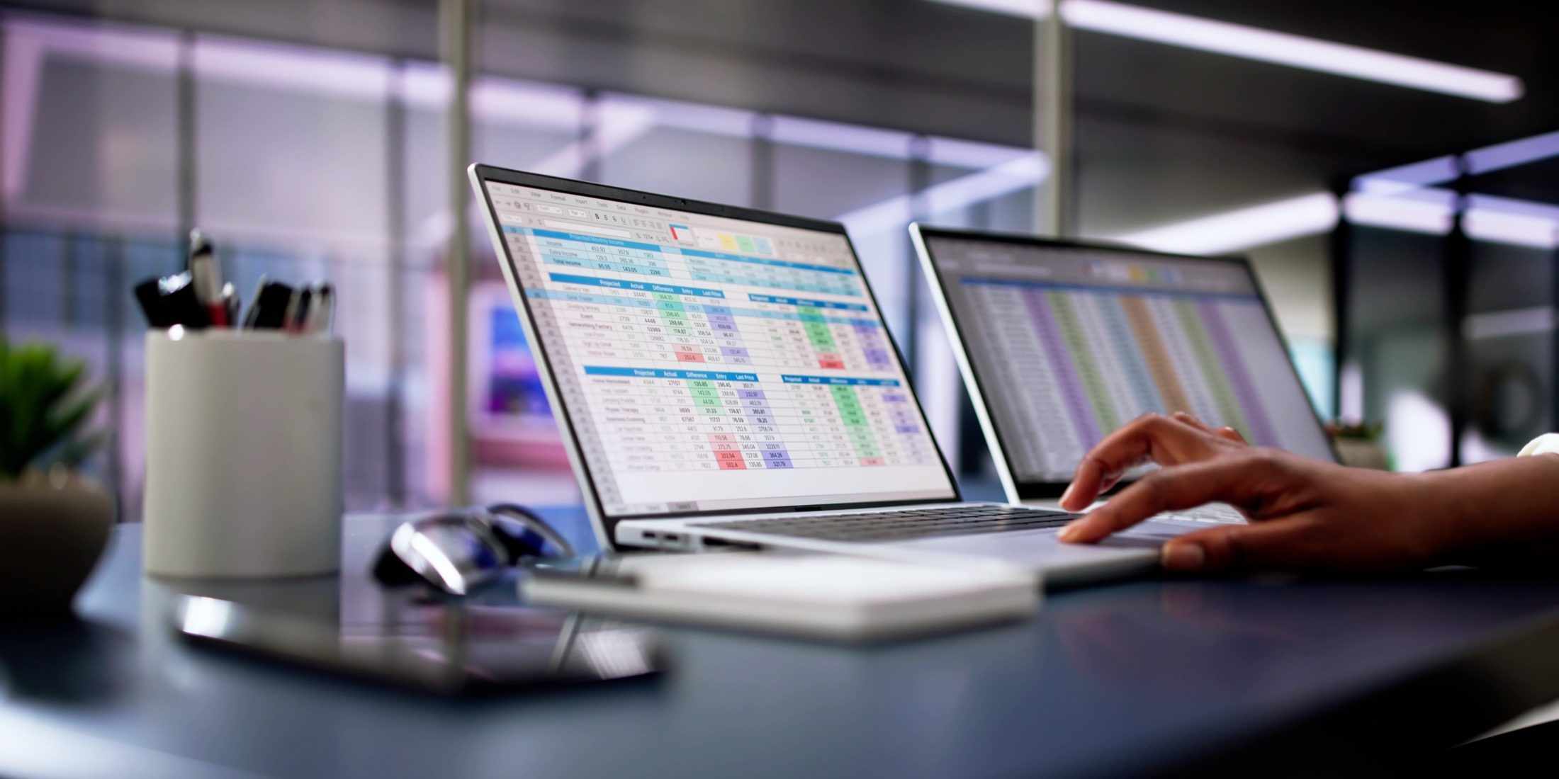 a desk with two computers with data tables