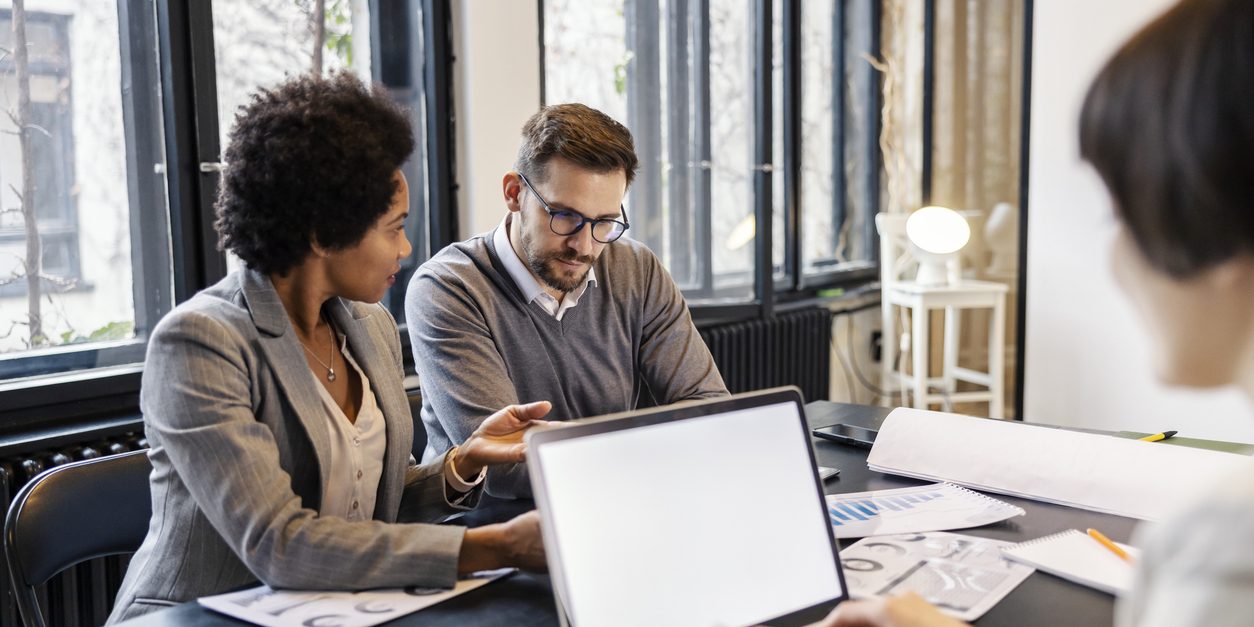 Interracial coworkers in meeting room having briefing and analyzing charts and graphs.