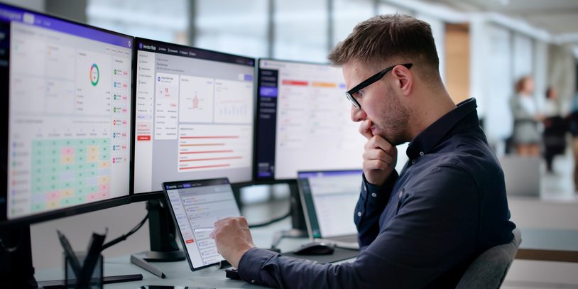 Man in front of rows of computer monitors