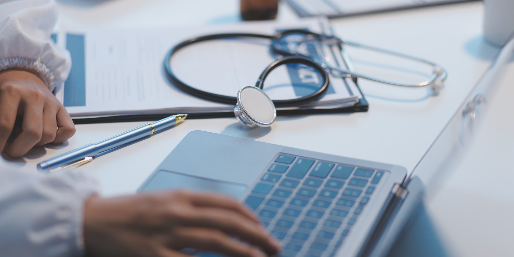 a desk with a stethoscope and a laptop